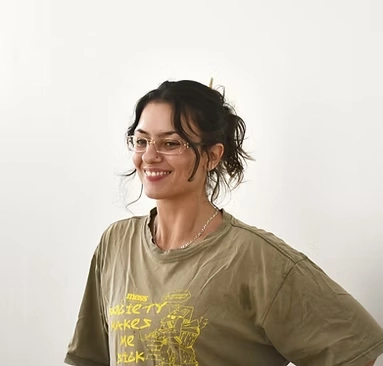 Mariana Mazzetti, pesquisadora de artes visuais, usando óculos e camiseta verde